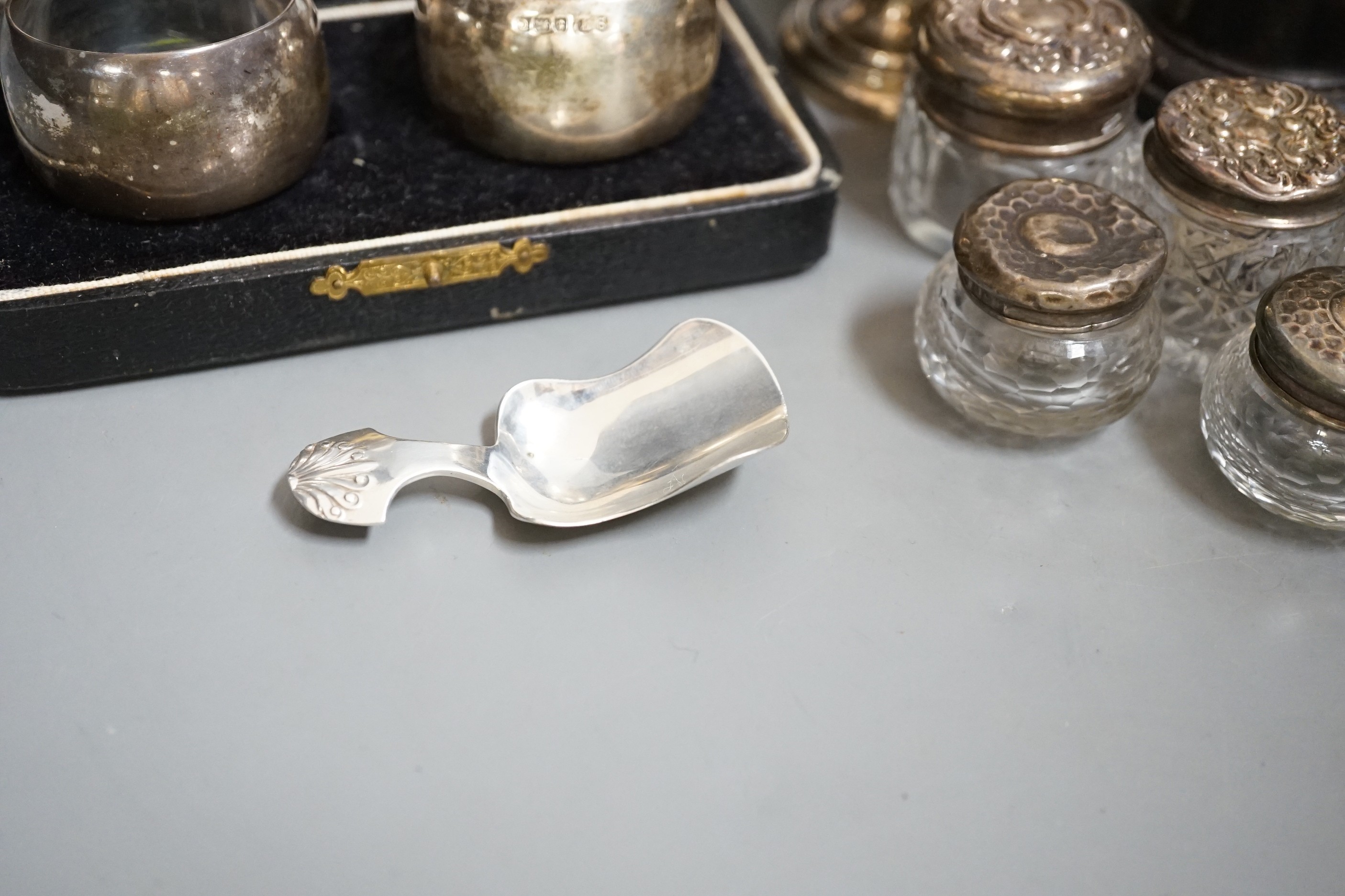 A Victorian repousse silver christening mug, Birmingham, 1861, 9.5cm, a cased pair of silver napkin rings, four assorted silver mounted toilet jars, a silver compact, small silver trophy cup and a silver caddy spoon.